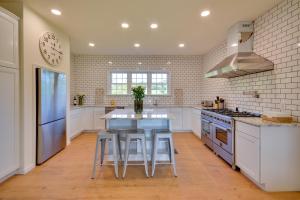 a kitchen with white cabinets and a blue island with stools at Timeless Hillsville Farmhouse Blue Ridge Parkway! in Ararat