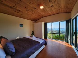 a bedroom with a large bed and a large window at Seven Island View in Hahei