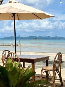 uma mesa com duas cadeiras e um guarda-sol na praia em Ursula Beach Resort em El Nido