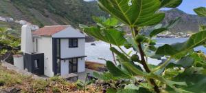 una pequeña casa en la orilla de un cuerpo de agua en Casa da Ponta Negra en Vila do Porto