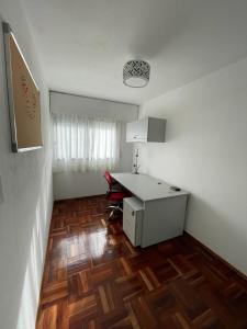 een witte kamer met een bureau en een houten vloer bij Apartamento recién renovado en Punta Carretas in Montevideo