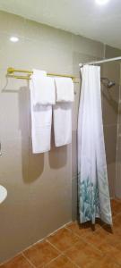 a bathroom with white towels and a shower curtain at Toafa Lodge in ‘Ohonua
