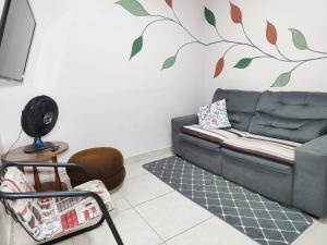 ein Wohnzimmer mit einem Sofa und einem Baumbild an der Wand in der Unterkunft Condomínio Capim Santo in Goiânia