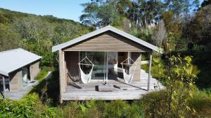 une petite maison avec une terrasse couverte dans un champ dans l'établissement One O One Cabins, Waiheke Island, à Oneroa