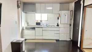 cocina con armarios blancos y nevera en Reynaville 4F / Vacation STAY 2134, en Tokushima