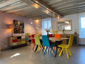 ein Esszimmer mit einem Tisch und bunten Stühlen in der Unterkunft La Guest beucherie in Romorantin