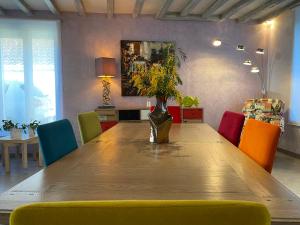 ein Esszimmer mit einem Holztisch und bunten Stühlen in der Unterkunft La Guest beucherie in Romorantin