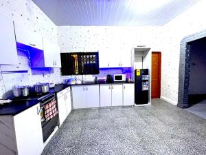 a kitchen with white cabinets and a black refrigerator at OLIVER COTTAGE GUESTHOUSE in Yamoransa