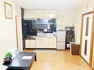 een kleine keuken met witte kasten en een tafel bij Reynaville 4F / Vacation STAY 3339 in Tokushima