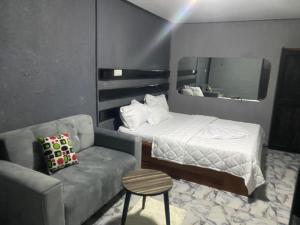 1 dormitorio con 1 cama, 1 sofá y 1 silla en Sunrise Center Bonapriso, en Douala