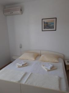 ein weißes Bett in einem Zimmer mit einem Bild an der Wand in der Unterkunft Apartments by the sea Tisno, Murter - 17716 in Tisno
