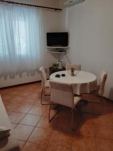 ein Wohnzimmer mit Tisch und Stühlen und einem Fernseher in der Unterkunft Apartments by the sea Tisno, Murter - 17716 in Tisno