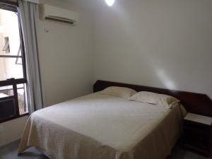 uma cama com duas almofadas num quarto com uma janela em Riviera Green Residence 232 em Bertioga