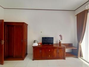 a room with a wooden desk with a television on it at Edu Hotel (Hotel Edukasi SMK PK) in Bangli
