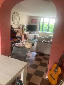 ein Wohnzimmer mit einer Gitarre an der Wand in der Unterkunft Le petit belge in Montgivray