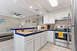 a kitchen with white cabinets and a stainless steel refrigerator at 2 Bed 1 Bath Condo By Beach & Entertainment in South Padre Island