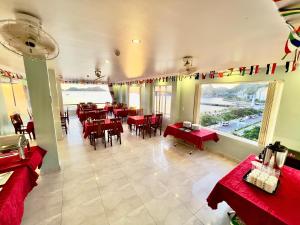 a restaurant with red tables and chairs in a room at Phoenix Flower Hotel in Cat Ba