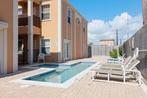 a swimming pool with a pair of chairs next to a house at Luxury 3 Bed 2 Bath 1st Floor Condo Near Beach in South Padre Island