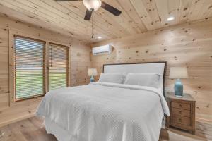 een slaapkamer met een wit bed en houten wanden bij Getaway Cottage - Creek Front, WIFI, Free Attraction Tickets in Cosby