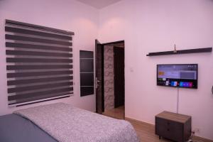 um quarto com uma cama e uma televisão na parede em Maydec+ Apartment em Jidu