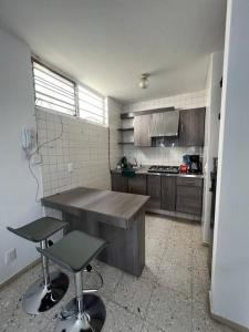 eine Küche mit einem Holztisch und 2 Hockern in der Unterkunft Cómodo Departamento en Providencia in Guadalajara