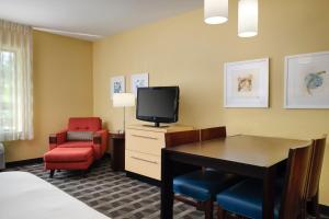 um quarto de hotel com uma secretária, uma televisão e uma cadeira em TownePlace Suites Ann Arbor em Ann Arbor