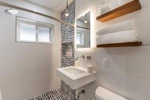 La salle de bains blanche est pourvue d'un lavabo et d'un miroir. dans l'établissement ASH and KO, à Phoenix