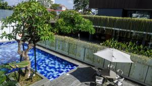 um guarda-sol e cadeiras junto a uma piscina em JW NAUNGAN COLIVING em Surakarta