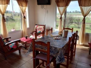 comedor con mesa, sillas y ventanas en Rincón del Sol en Gardey