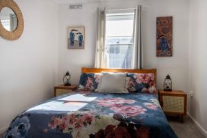 a bedroom with a bed with a floral bedspread and a window at A Wave from it All in Berrara