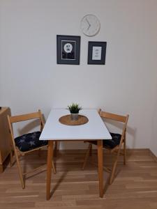 a white table with two chairs and a clock on the wall at Adam apartmán in Košice