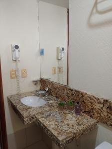 a bathroom with a sink and a large mirror at Natal Plaza Suítes- Ponta Negra in Natal