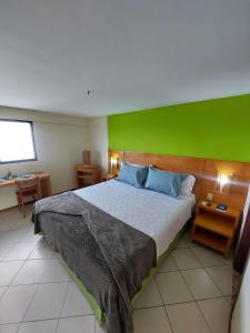 a bedroom with a large bed with a green wall at Natal Plaza Suítes- Ponta Negra in Natal