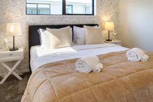 a bedroom with a large bed with towels on it at Beachside Bliss: 1 Bed 1 Bath in Christchurch +20 photos