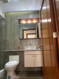 a bathroom with a toilet and a sink and a mirror at Sucre Suites Cuenca in Cuenca