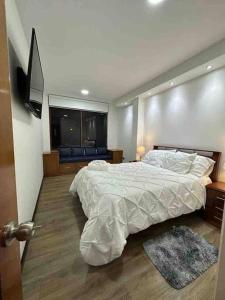 a bedroom with a large bed and a flat screen tv at Sucre Suites Cuenca in Cuenca