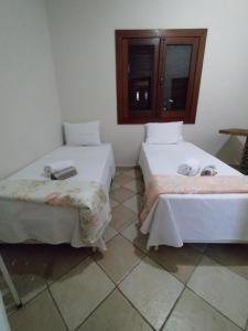 two beds in a room with a tiled floor at Recanto Pau Brasil in Sete Lagoas