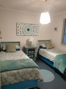 a bedroom with two beds and a table with a lamp at Aqua Shack Jurien Bay in Jurien Bay