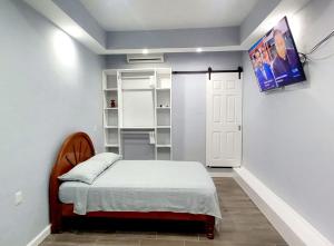 Un dormitorio con una cama y un televisor en la pared. en Departamento María. La Crucecita Huatulco., en Santa Cruz Huatulco