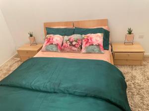 1 cama con edredón verde y 2 mesitas de noche en City Sky Place en Mánchester