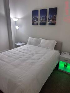 een slaapkamer met een wit bed met twee foto's aan de muur bij Luxurious 2 Bedroom Downtown City Views! in Indianapolis