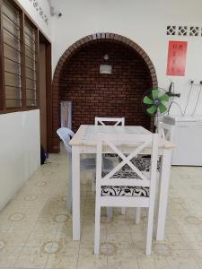 a white table and chairs in a room with a brick wall at Happy Bentong Guest House in Bentong