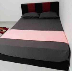 a large bed with a black and pink comforter at Afrinas Homestay @ Banting in Banting