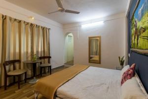 1 dormitorio con 1 cama, mesa y sillas en Tabletop Villa Standard - 2, en Panchgani