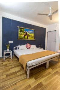 1 dormitorio con 1 cama grande y pared azul en Tabletop Villa Standard - 2, en Panchgani