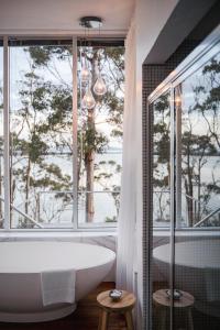 a bathroom with a tub and a large window at Baragoola Retreat - Luxury Waterfront Property in Sandford
