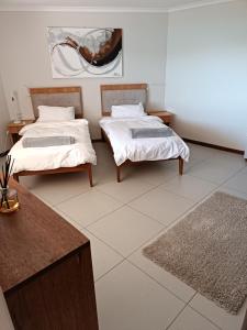 a room with two beds and a table and a rug at Sunset Villa in Langebaan