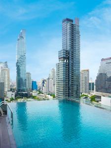 a large swimming pool in a city with tall buildings at Amara Bangkok Hotel in Bangkok