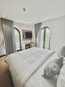 Schlafzimmer mit einem großen weißen Bett und Fenstern in der Unterkunft La Sera Suites Nha Trang in Nha Trang