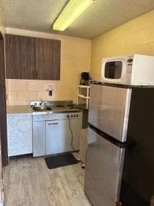eine Küche mit einem Kühlschrank und einer Mikrowelle in der Unterkunft Road Runner Motel Merritt BC in Merritt